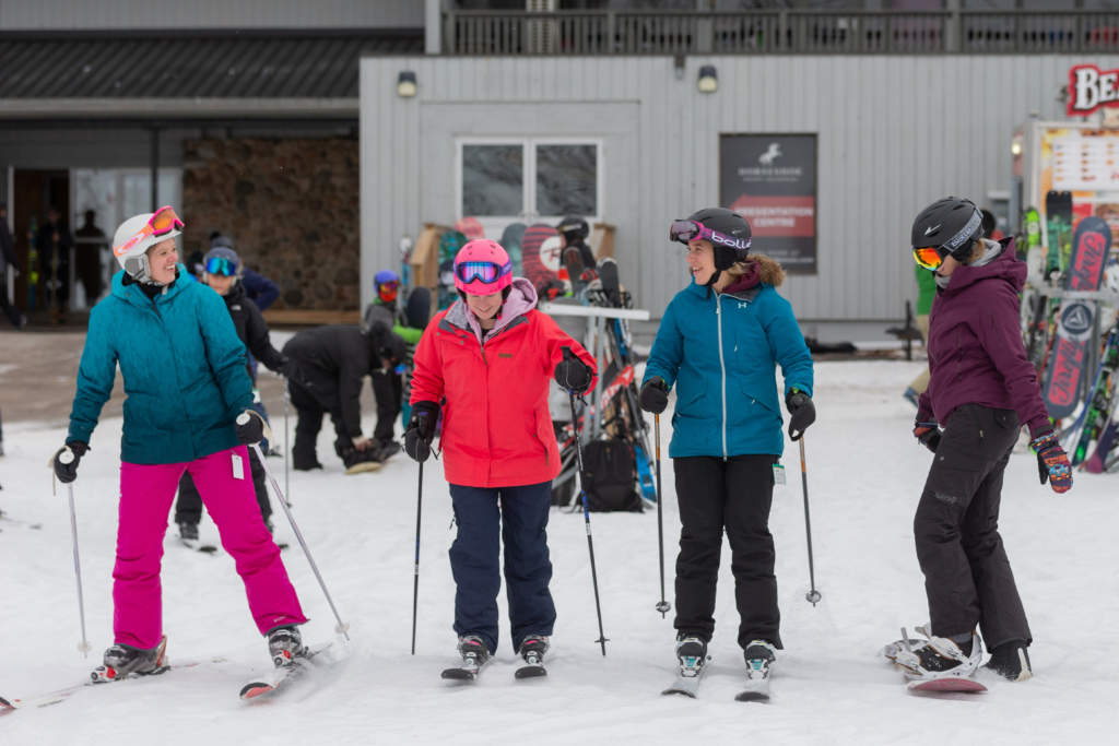 Female skiers and snowboard in front of chalet