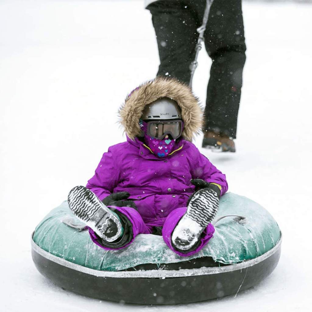 child sitting in snow tube