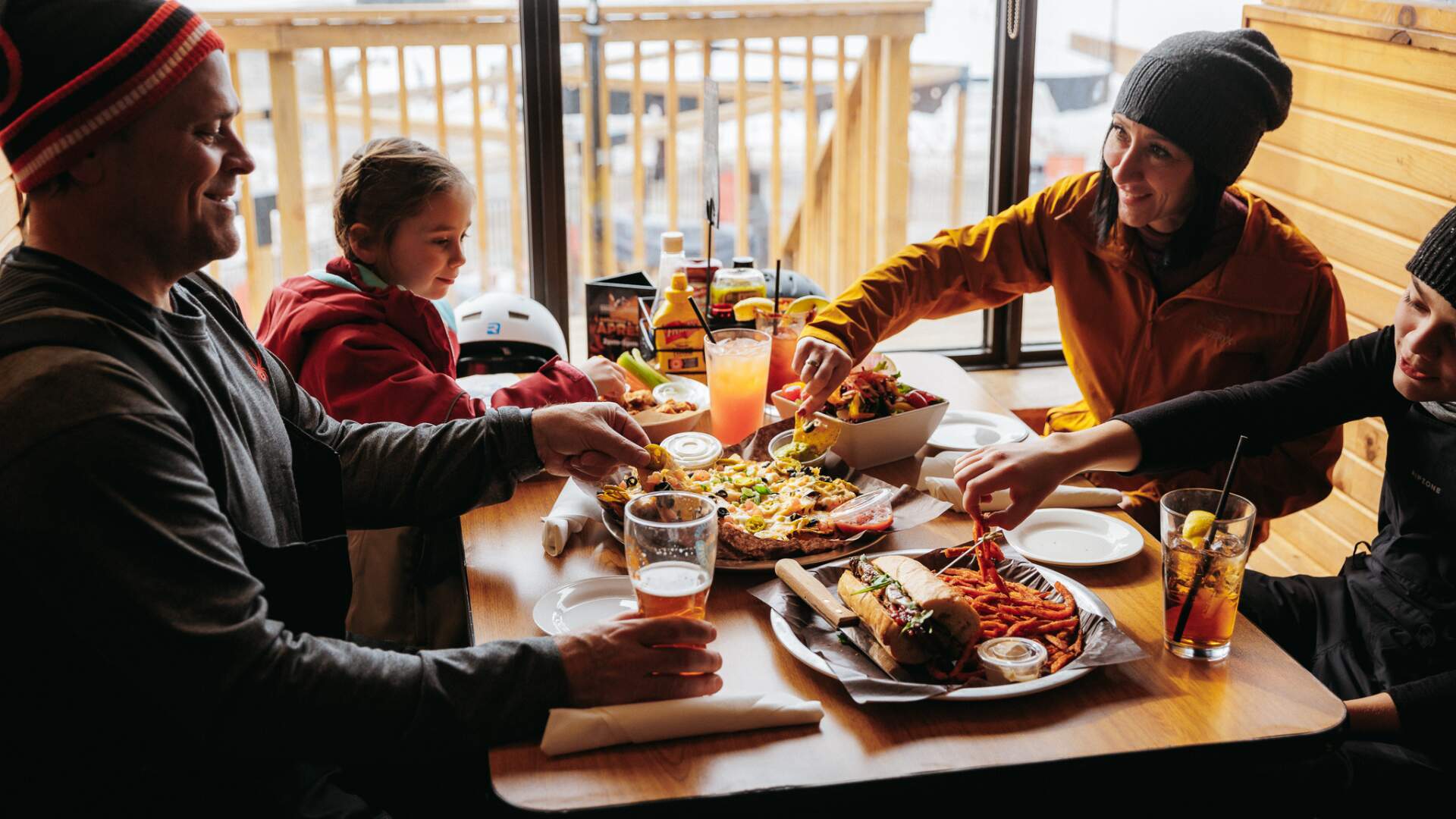 parents and children eating an array of nachos, sandwiches, drinks and beer
